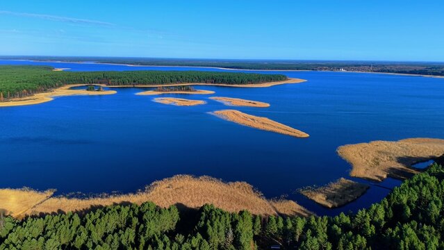 Aerial view of serene blue lake surrounded by lush green forests and sandy shorelines