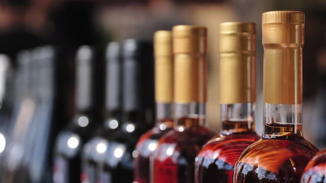 Bottles of wine and alcohol in a row with selective focus on the golden caps