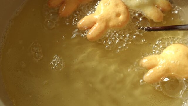 Close up of golden brown rabbit shaped cookies frying and being turned