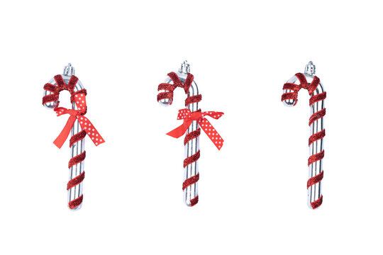 Set of three silver candy cane ornaments wrapped in red glitter, with two featuring a polka dot bow. Isolated on white, these are ideal for winter holiday and Christmas mockups.