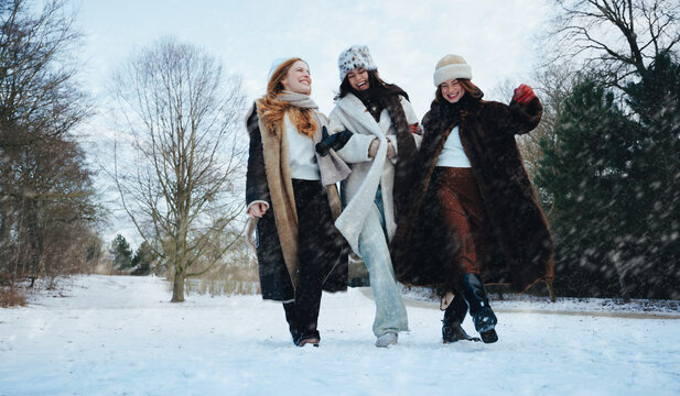 Women walk laughing together in a snowy winter park