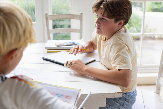 pre teen and early teen boy doing homework together in light filled room