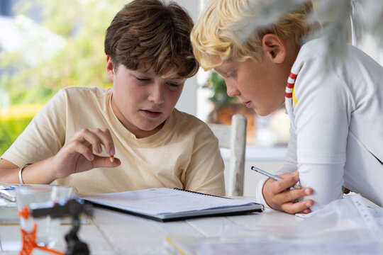pre teen and early teen boy doing homework together in light filled room