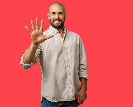 Man caucasian with beard, young wearing casual clothes showing number five fingers pointing up, happy, smiling and confident, point gesture studio portrait