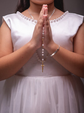 Close-Up of Young Girl Praying with a Golden Crucifix Rosary