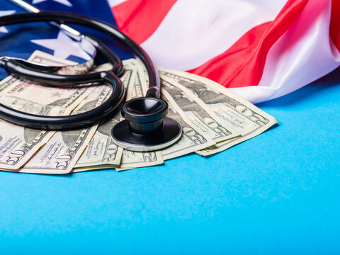 Black Stethoscope on US Dollar Bills and American Flag Representing Healthcare Costs