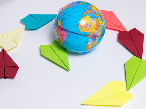 World Globe Surrounded by Colorful Origami Paper Airplanes