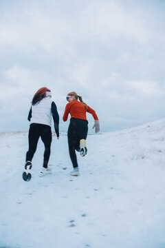Women race playfully to the hilltop in snowy winter running session