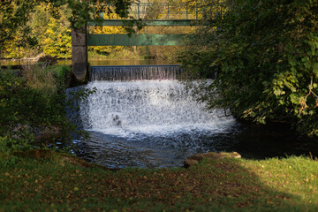 Water cascades over a small dam under a green bridge © nicholasjermy