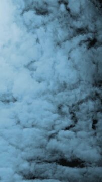 Vertical video: Camera moving inward as bluish cloud mass drifting, edges rolling to reveal texture