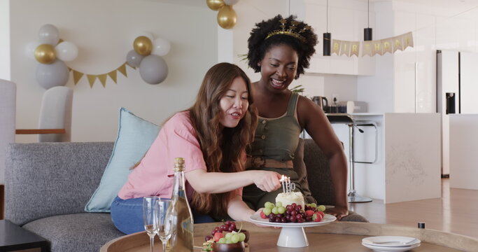 Happy black and korean lesbian couple making surprise, celebrating, clapping hands and lighting cand