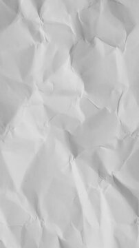Vertical video: Subtle camera pan revealing crumpled paper creases and shadows for texture study