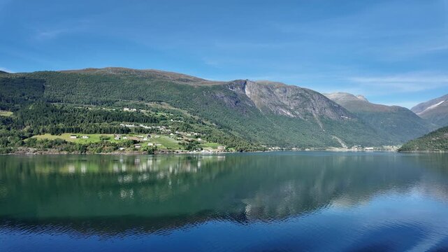 The view looking across the water towards the Norwegian village of Loen. The village is found at the innermost part of Nordfjord, a highly scenic body of water in the Norwegian Fjords.