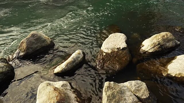 Close-up shot of flowing water in the upper section and calm water surface around river rocks in Hayakawa River Hakone