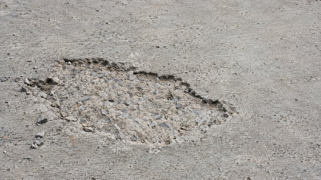 Shallow concrete spalling exposing aggregate below a worn gray surface