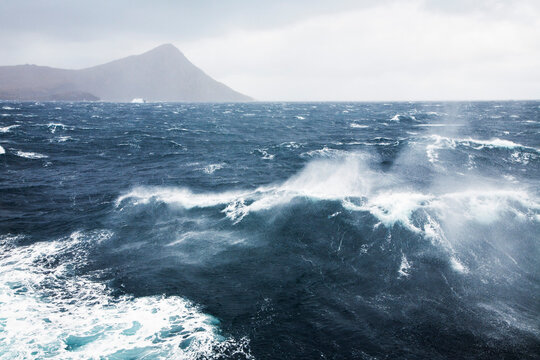 Rough sea with waves near rocky island at Cape Horn National Park