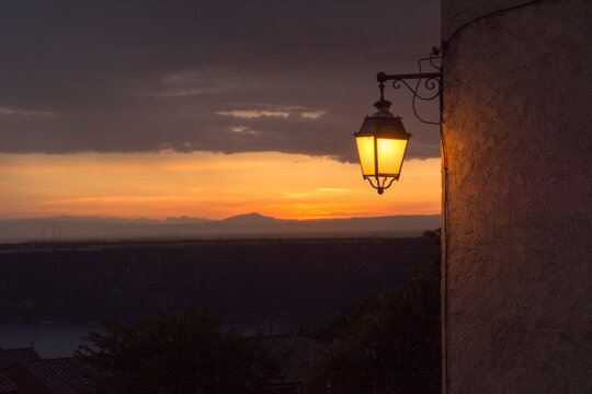 Street lamp glowing at sunset in Aiguines village