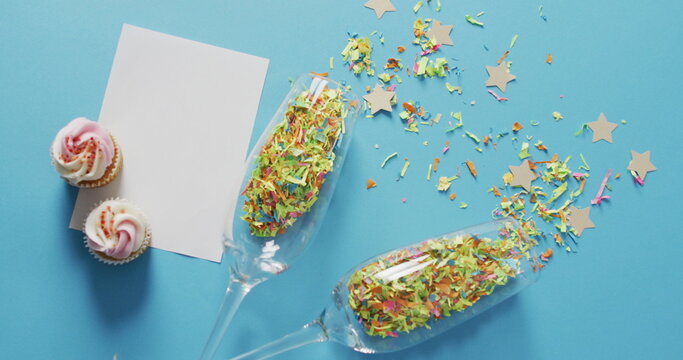 Champagne glasses with confetti and white card on blue background at new year's eve