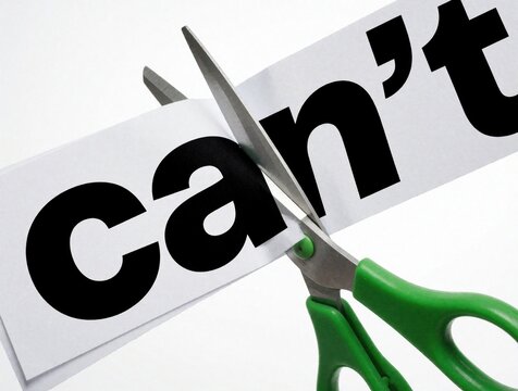 Green scissors cut through paper with word cant printed in black. Metal blades slice text to remove negativity. Concept of overcoming obstacles, changing mindset, finding success. Breaking limits,
