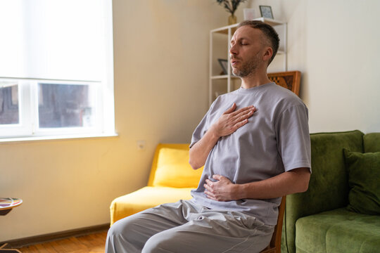 Mindful breathing and anxiety relief practice, middle aged man doing calming breathwork and stress management exercise at home for meditation and mental wellbeing