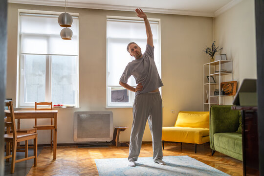 Morning stretching exercise for mobility and flexibility at home, middle aged man performing standing side bend for daily fitness, posture improvement and healthy lifestyle