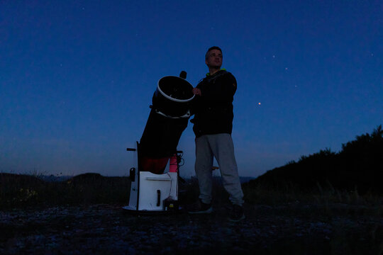 Amateur astronomer observing stars, planets, Moon and other celestial objects with a telescope in nature.
