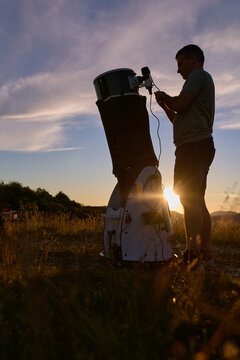 Amateur astronomer preparing telescope during sunset for night observations of stars, Milky Way, Moon and Planets.