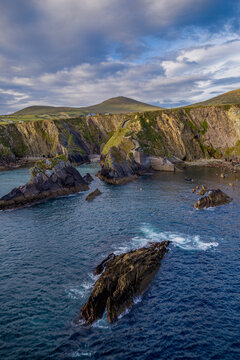 Scenic coastal landscape of Dunquin Pier on the Dingle Peninsula, County Kerry, Ireland.  Winding pedestrian path leading down steep, green clifftops to  secluded rocky harbor.