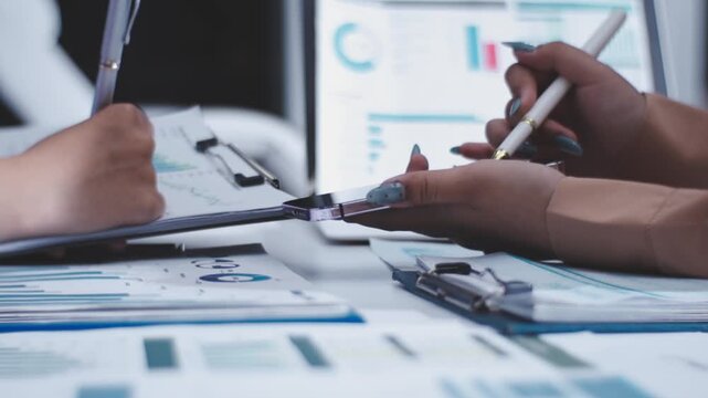 Two female accountants counting on calculator income for tax form completion hands close-up. Business and audit concept