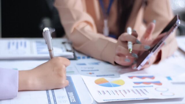 Two female accountants counting on calculator income for tax form completion hands close-up. Business and audit concept