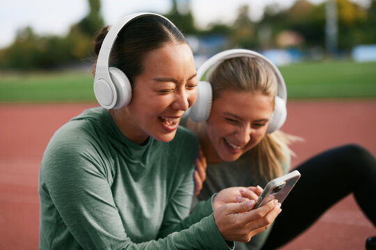 Women laughing while looking at a smartphone on the track