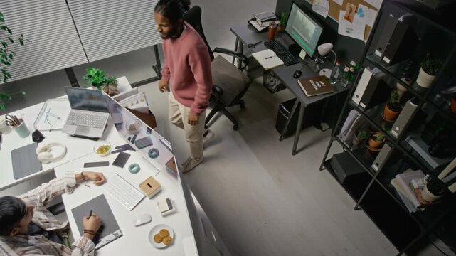Young adult Asian and Indian male CGI specialists collaborating at office desks, using computer and graphic tablet. Clip suitable for digital media, IT agency, and tech workforce campaigns
