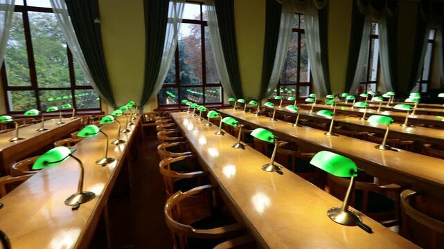Empty historic library reading room with green banker lamps on wooden desks by autumn windows