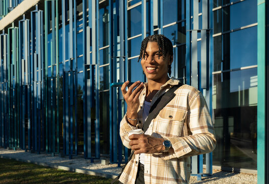 Young man talking on phone holding coffee outdoors