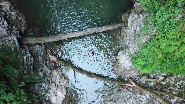 Aerial top view of the majestic Azhek Waterfall cascading down a steep rocky cliff surrounded by lush green forests in Sochi, Russia.