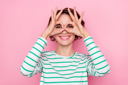 Portrait of attractive cheerful girl showing double ok-sign binocular watch cinema isolated over pink pastel color background