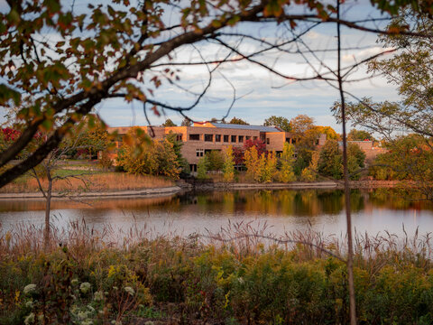 Naperville Police Department building framed by autumn trees across Lake Osborne on a calm fall day in Illinois