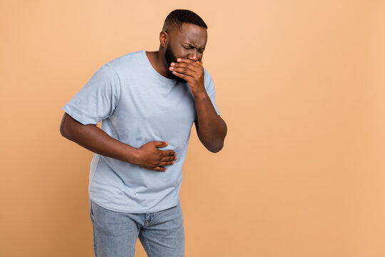 Portrait of attractive sick guy feeling bad nausea coughing isolated over beige pastel color background