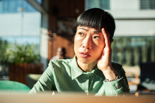 Worried woman holding her head in a cafe
