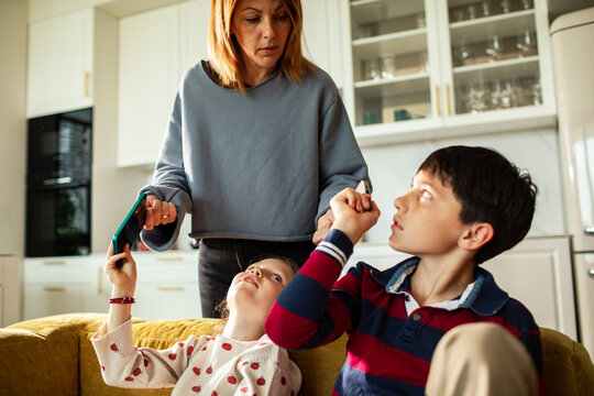 Parent taking away devices from kids on the couch