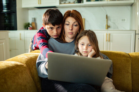 Mother with son and daughter looking at laptop on couch