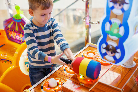 Young boy playing whack - a - mole arcade game at amusement center