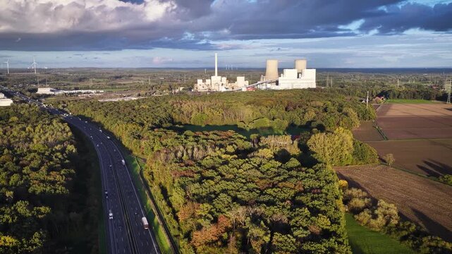 Aerial footage of traffic moving along the A2 highway with the industrial chimneys and cooling towers of a coal-fired power station in Germany.