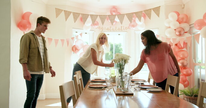 Happy white and multiracial friends preparing plates and decorations for party at home with congratu