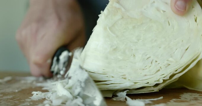 Close-up male hands cut cabbage with knife on wooden cutting board. 4K 10-bit