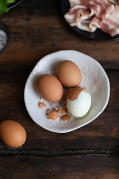 Hard-boiled eggs with partial peeling on rustic kitchen table