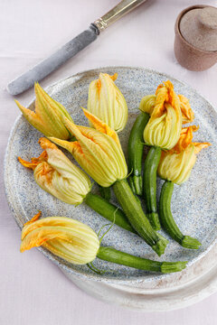 Fresh zucchini flowers with mini zucchini on ceramic plate