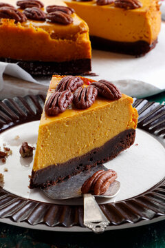 Pumpkin cheesecake slice with chocolate base and pecan topping