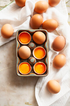 Brown eggs and cracked yolks in ceramic egg container