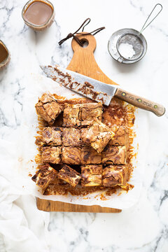 Cheesecake brownies cut into squares on wooden board